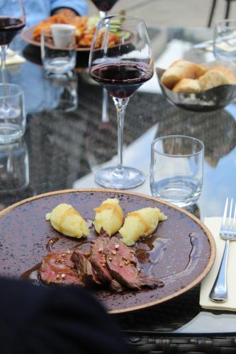 a plate of meat and a glass of wine on a table at Hôtel Restaurants & Spa Perier Du Bignon in Laval