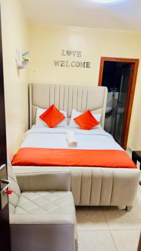 a white bed with orange pillows in a room at Rosette Haven 2 in Nairobi