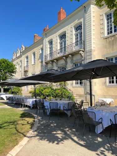 a group of tables with umbrellas in front of a building at Hôtel Restaurants & Spa Perier Du Bignon in Laval