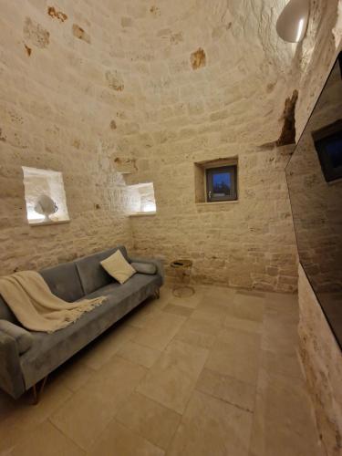 a living room with a couch and a stone wall at Stylish Trullo Pool Villa in Martina Franca