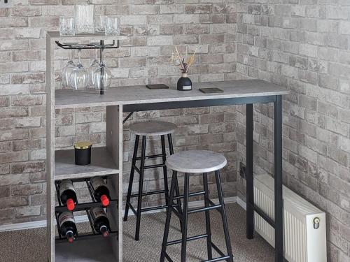 a table with two stools next to a brick wall at Zion's Retreat in Plumbland