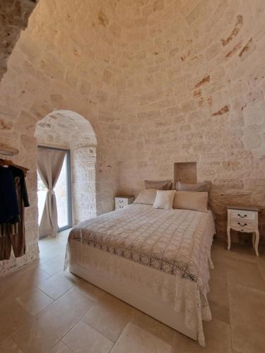 a bedroom with a large bed in a stone wall at Stylish Trullo Pool Villa in Martina Franca