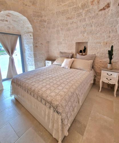 a bedroom with a bed and a stone wall at Brunaldi Trulli Pool Villa in Martina Franca