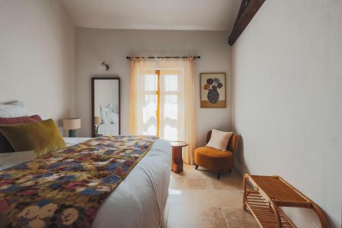 a bedroom with a bed and a chair and a window at Les Terrasses de la Borie in Mandagout