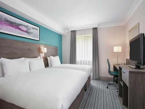 a hotel room with two beds and a flat screen tv at Leonardo Hotel East Midlands Airport - Formerly Jurys Inn in Castle Donington