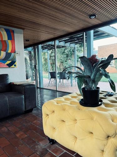 a living room with a yellow ottoman with a plant at Peaamb GuestHouse - Springs Golf Club in Springs