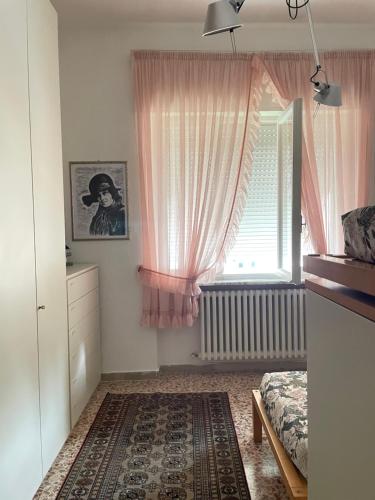 a bedroom with a bed and a window with pink curtains at Ars in Villa in Livorno