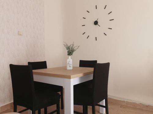 a dining room table with chairs and a clock on the wall at Apartamento DECO Center Ciudad Real in Ciudad Real