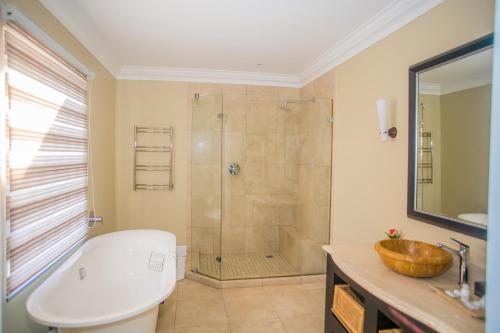 Un baño con ducha con bañera y lavabo. en The Presidential Mansion, en Durban