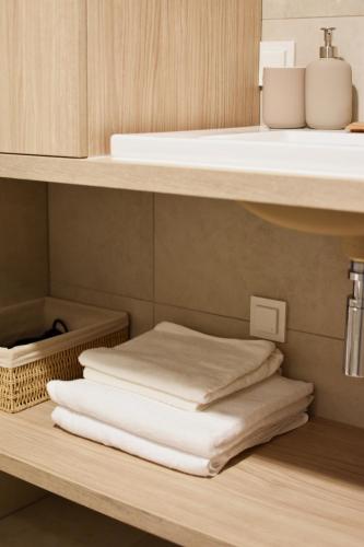 a stack of towels on a shelf under a sink at Nidos Banga in Nida