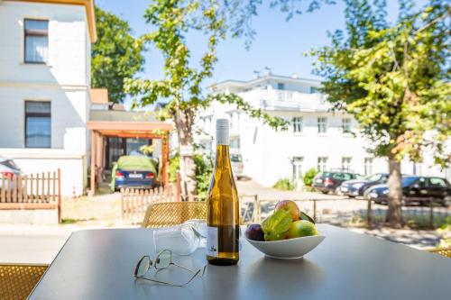 una botella de vino y un bol de fruta en una mesa en Quartier 7 App 03, en Ahlbeck