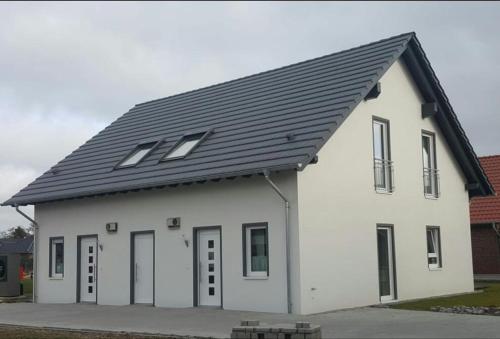 une maison blanche avec un toit noir dans l'établissement Haus Luv & Haus Lee - Nordseebad Burhave, à Burhave