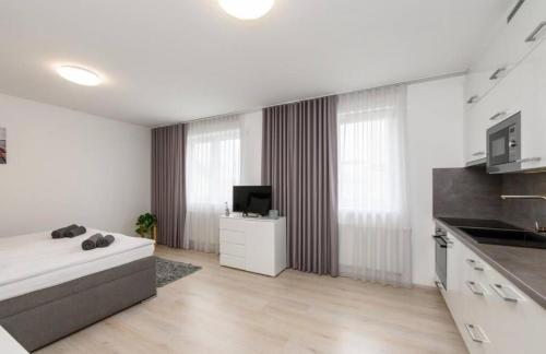 a white room with a bed and a television in it at Urban nest Pilsen in Plzeň