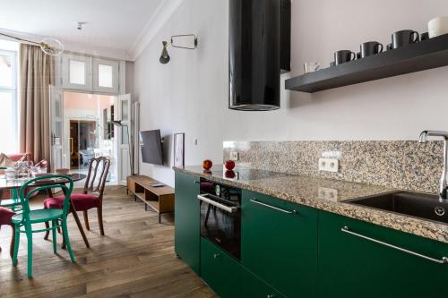 a kitchen with green cabinets and a table with chairs at Fragola Apartments Old Town in Kraków