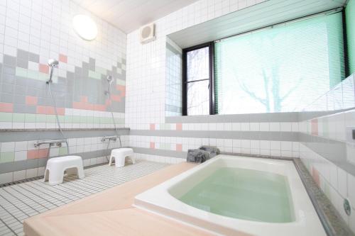 a bathroom with a tub and two stools at 里山でのんびり遊べる宿-風音翆舎 Kanon suisha in Kawaba