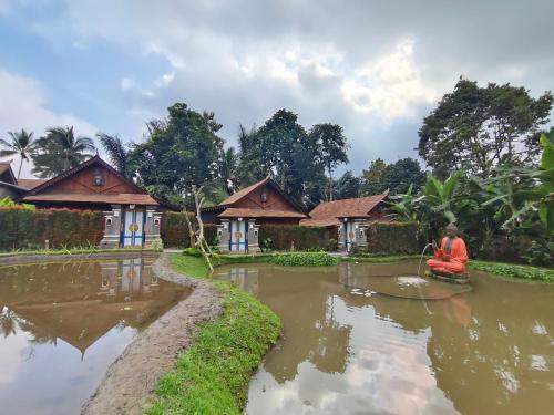 a person sitting on a raft in a river in front of houses at Lawani Resort in Tegalalang