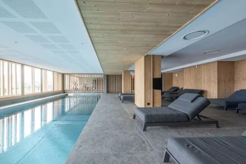 a swimming pool with couches and chairs in a building at Alpe d'Huez Houses - L'Emparis - PHOENIX3 - Pour 5 SKI IN SKI OUT Wellness et vue magnifique in L'Alpe-d'Huez