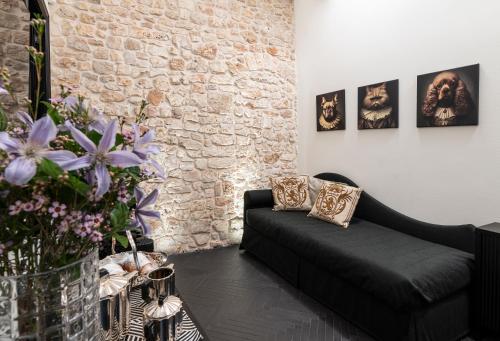 a living room with a black couch and a brick wall at Dimora San Nicola Charming Suite in Conversano