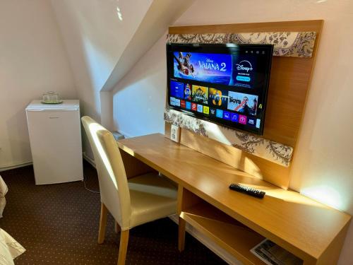 a room with a desk with a television on a wall at Fészek Fogadó - Pension Nest in Mosonmagyaróvár
