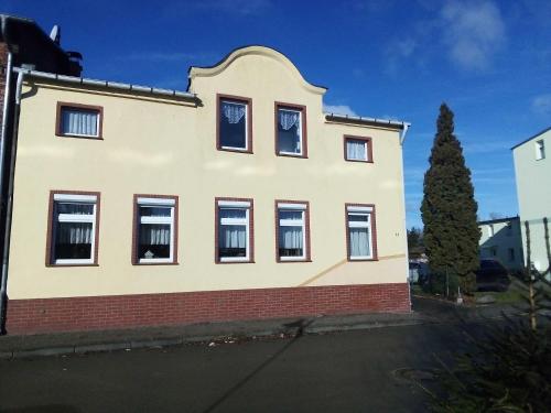 ein weißes Haus mit schwarzen Fenstern und einem Baum in der Unterkunft Ferienwohnung am Yachthafen in Ueckermünde