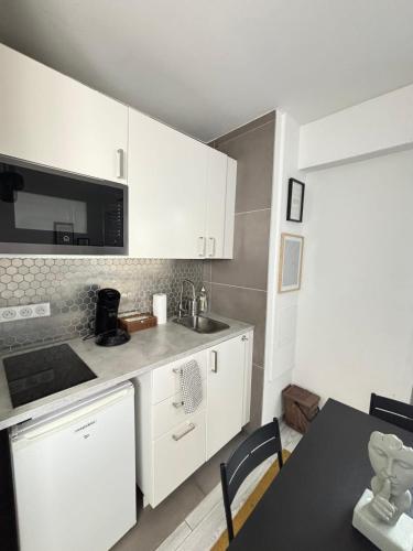 a kitchen with white cabinets and a sink and a table at Soh Rent Strasbourg Wifi Terrasse St Aloise in Strasbourg