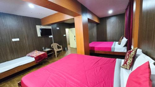 a room with two beds with pink sheets and a tv at Mananya Cottage Ooty in Ooty