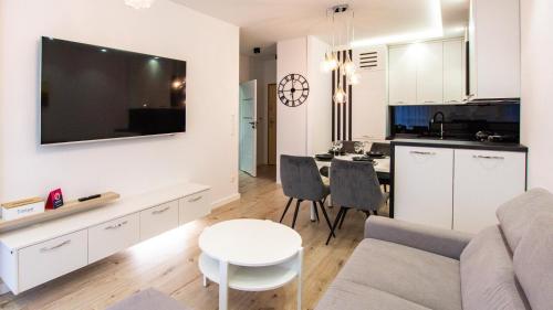 a living room with a couch and a table and a kitchen at VacationClub Let's Sea Baltic Park Apartament A20 in Gąski