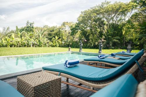a pool with two lounge chairs and a swimming pool at Tropical Space in Ubud