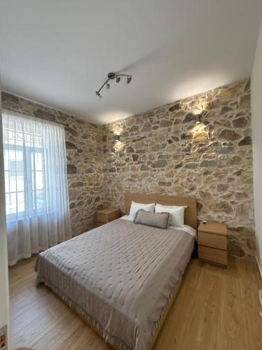 a bedroom with a bed and a stone wall at Garden Residence in Ermoupoli