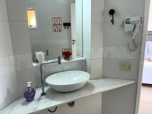 a white bathroom with a sink and a mirror at Sol & Aconchego Paraty in Paraty