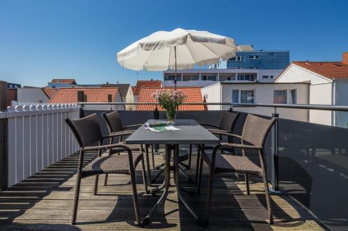 a table and chairs on a balcony with an umbrella at Robbenloft in Norderney