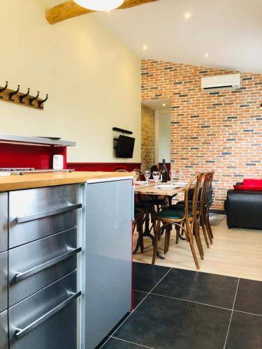 a kitchen and dining room with a table and a brick wall at L'Aubergiste in Corcelles-les-Arts