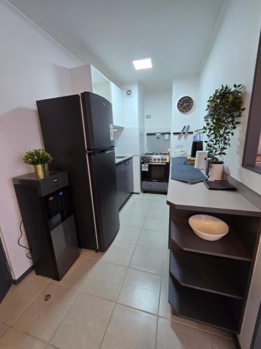 a large kitchen with a black refrigerator in it at Espléndido y central Departamento Familiar in Rancagua