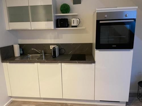 a white kitchen with a microwave and a sink at Apartment Alte Molkerei in Worpswede
