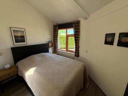 a bedroom with a bed and a window at Zeester 189 in Julianadorp