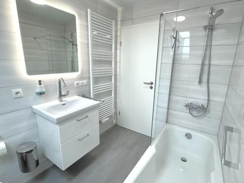 une salle de bain blanche avec lavabo et douche dans l'établissement Ferienhaus Meerwunder, à Wangerland