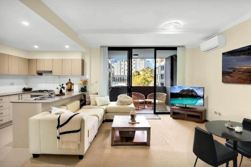 a living room with a white couch and a kitchen at 2 Bedroom Near Nepean Hospital & Penrith in Kingswood