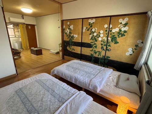 a room with two beds and a wall with flowers at ゲストハウス樹 in Shingu