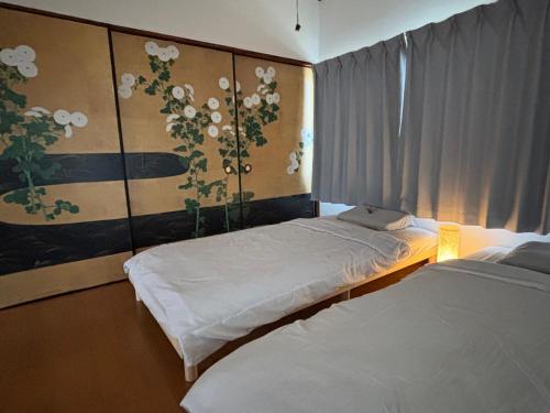 a bedroom with two beds and a painting of flowers at ゲストハウス樹 in Shingu