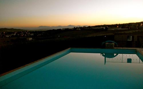a swimming pool with a sunset in the background at Il Gallo Del Vicino in Monte Urano