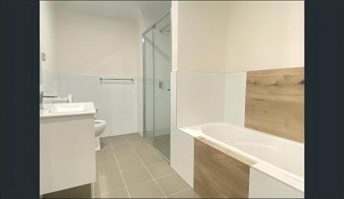 a bathroom with a tub and a sink and a toilet at 2 Bedroom Near Nepean Hospital & Penrith in Kingswood