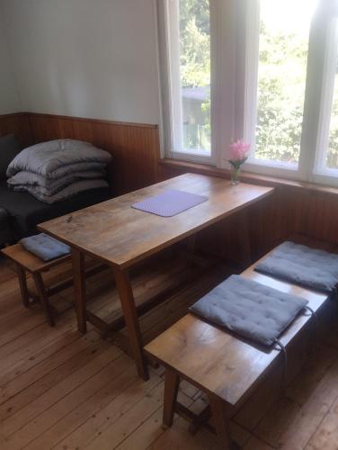a room with a wooden table and a bench and windows at Domek v přírodě Hradec Králové in Hradec Králové