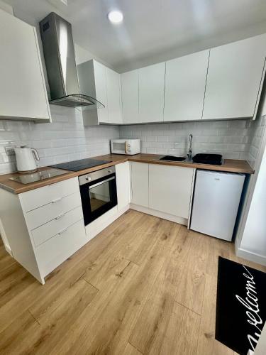 a kitchen with white cabinets and a wooden floor at The Studio - Private Car Park with CCTV - Fast WiFi - Peaceful Retreat with Views for Business or Couples in Oldbury