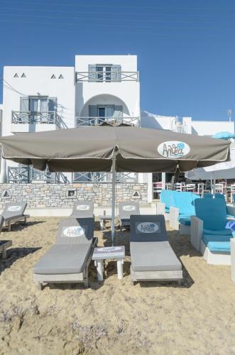 two lounge chairs and an umbrella on a beach at Naxian Althea in Agia Anna Naxos
