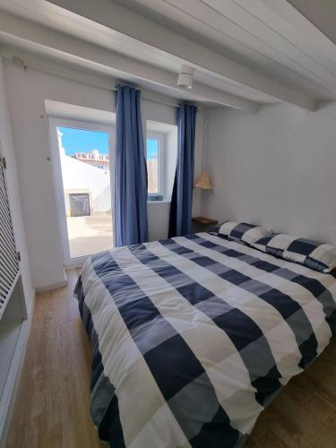 a bedroom with a bed with a blue and white checkered blanket at Casa Lagoa in Lagoa