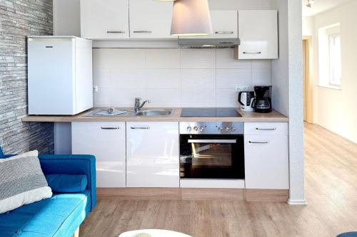 cocina con armarios blancos y sofá azul en Ferienwohnung Kamske, en Lübbenau