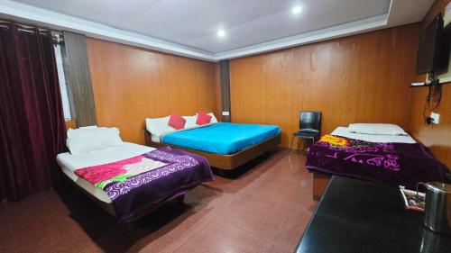 a room with two beds and a tv in it at Mananya Cottage Ooty in Ooty