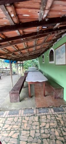 a picnic table and a bench under a roof at Camping Refugio SacodoCeu2026 in Saco do Ceu