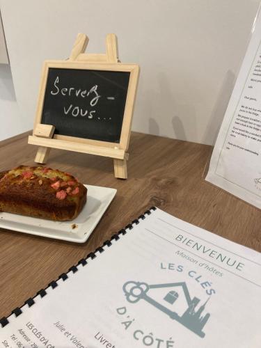 a table with a cake on a plate and a chalkboard at Les clés d'à côté - maison d'hôtes de charme près de Rouen in Sotteville-lès-Rouen