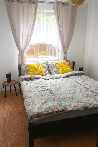 a bedroom with a bed with yellow pillows and a window at Apartament Marzenie in Kowary